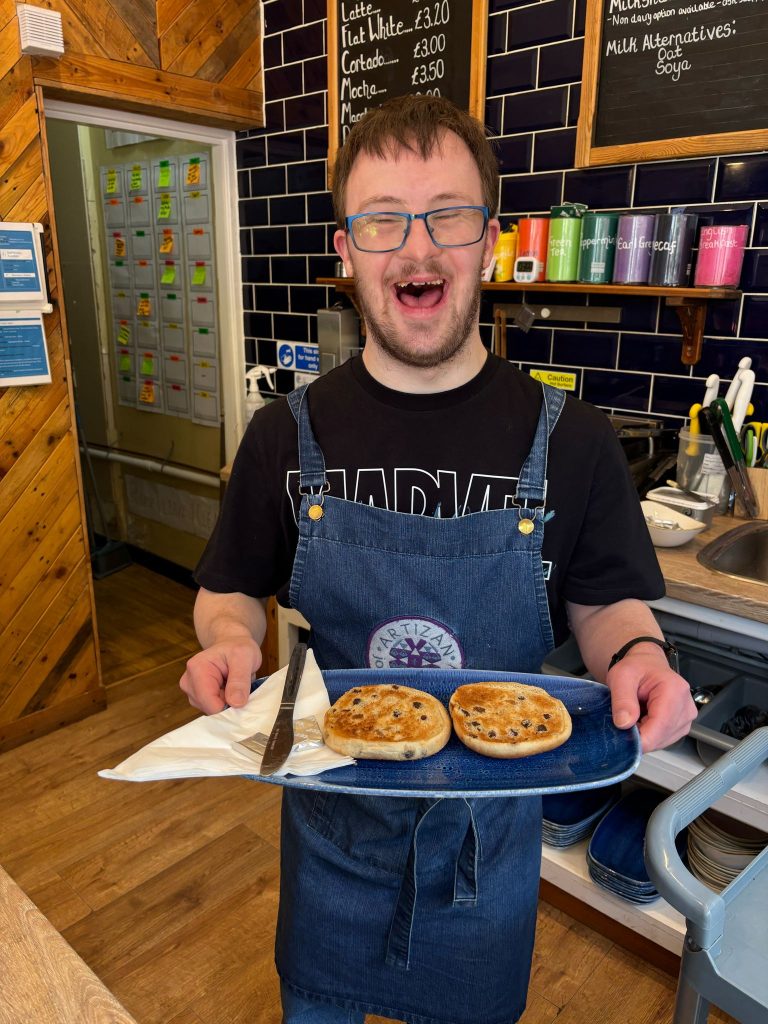 A waiter at our Harrogate Cafe serving toasted teacakes