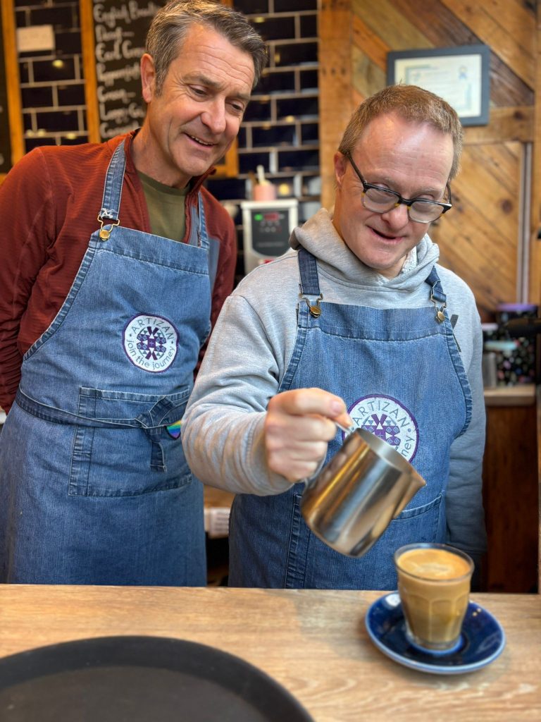 A waiter at our Harrogate Cafe pouring frothed milk into a coffee