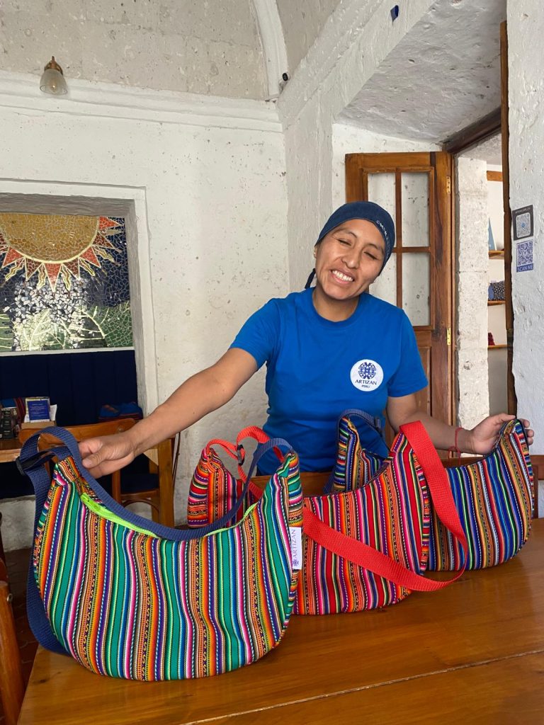 A volunteer in Peru holding 3 handmade bags