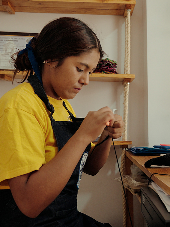 A young girl sewing at Artizan Peru